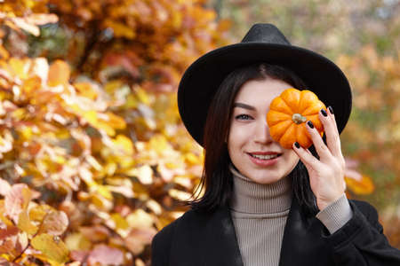 Woman in black hat with Halloween pumpkin in autumn forest, witch characterの写真素材