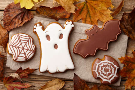 Halloween gingerbread cookies on wooden table with autumn leavesの写真素材