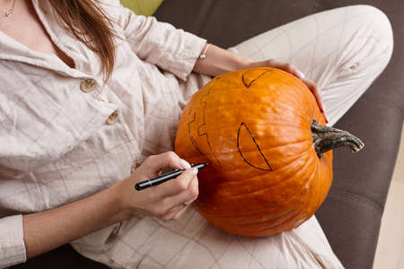 Woman painting pumpkin face and making jack lantern for Halloweenの写真素材