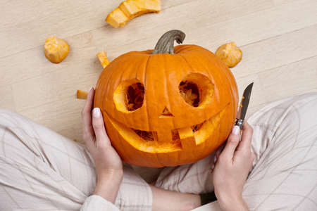 Woman cutting scary pumpkin jack for Halloween, holiday preparationの写真素材