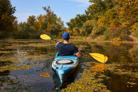Man kayaking on lake in autumn, back view. Active tourism.の写真素材
