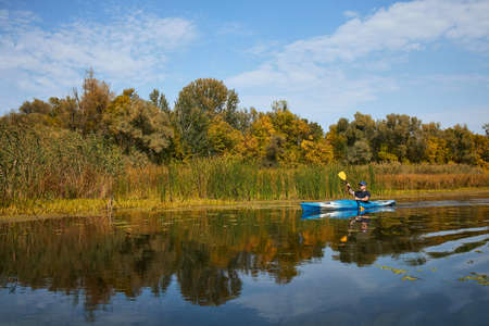 Man kayaking on lake in autumn. Active tourism.の写真素材