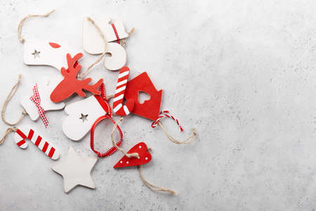 Red and white vintage wooden Christmas ornaments on textured white background, copy space. Holiday...
