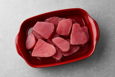 Raw tuna fish slices in deep red dish on gray stone backgroundの写真素材