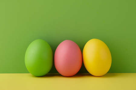 Painted Easter eggs on green and yellow background, spring holiday preparationの写真素材