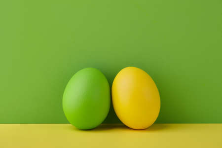 Painted Easter eggs on green and yellow background, spring holiday preparationの写真素材
