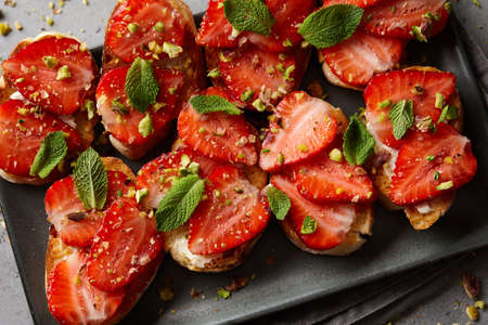 Bruschetta with fresh strawberries, pistachio nuts and mint leaves, close up viewの写真素材