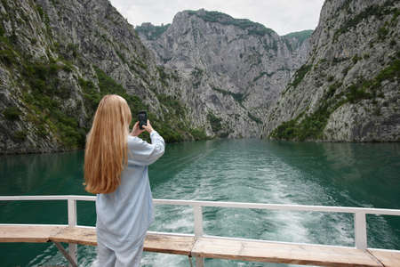 Blonde woman enjoying mountain view on a ferryの写真素材