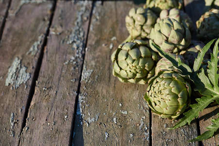 Fresh artichoke globes on wooden table in gardenの写真素材