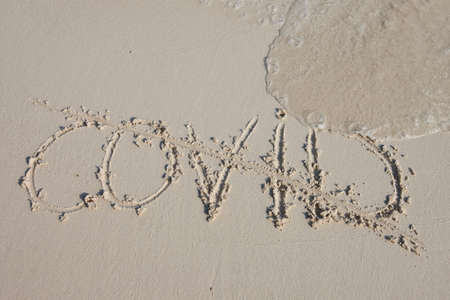 Word Covid crossed out on sea sand beach, conceptual.の写真素材