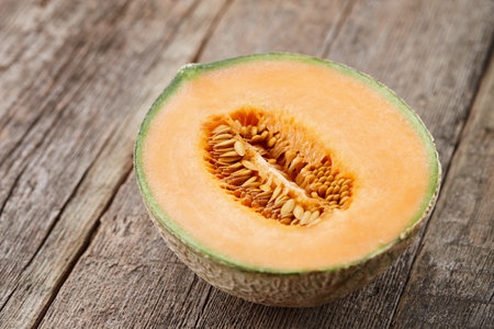 Half of cantaloupe melon on old wooden planks, close up viewの写真素材