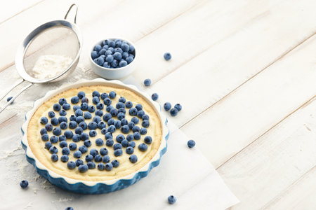 Blueberry pie or tart with fresh berries on white wooden tableの写真素材