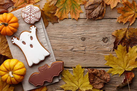 Halloween gingerbread cookies and autumn leaves on wooden planks, copy spaceの写真素材