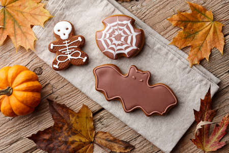 Halloween gingerbread cookies and autumn leaves on wooden planksの写真素材