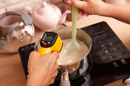 Measuring temperature of sweet syrup. Confectioner making sweets in the kitchen.の写真素材