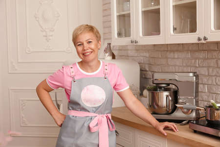 Woman confectioner smiling portrait in apron, kitchen interiorの写真素材