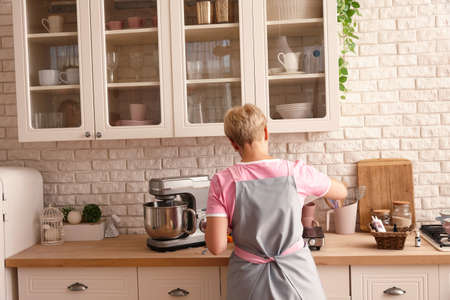 Woman confectioner making sweets in the kitchen, back viewの写真素材