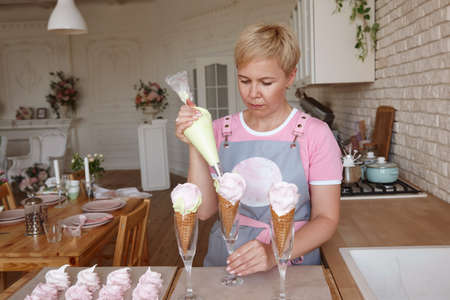 Confectioner making marshmallow desserts with pastry bag in the kitchenの写真素材