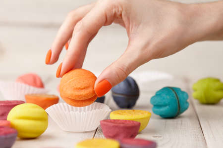 Womans hand taking color cookie from tableの写真素材