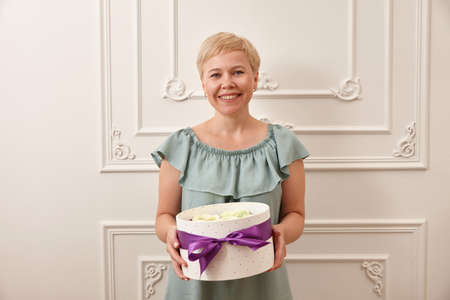 Woman confectioner smiling with sweets box on white backgroundの写真素材