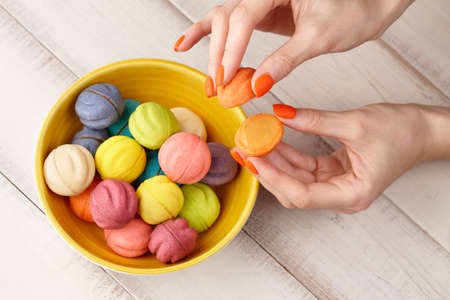 Woman taking color cookies from bowl, hands close upの写真素材