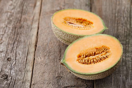 Halves of cantaloupe melon on old wooden planks, close up viewの写真素材