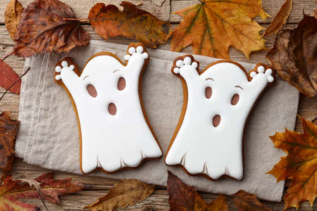 Halloween gingerbread cookies and autumn leaves on wooden planks, white ghostsの写真素材