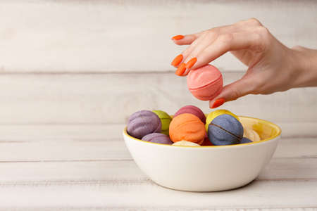 Woman taking color cookies from bowl, hands close up viewの写真素材
