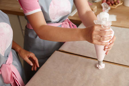 Pastry chef team making marshmallow desserts with bag, close up viewの写真素材