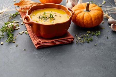 Pumpkin soup with thyme herb, cream and pumpkin seeds served in orange pumpkin shaped bowlの写真素材