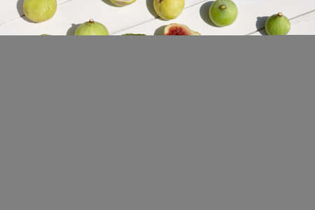 Fresh green figs with leaves on white wooden tableの写真素材