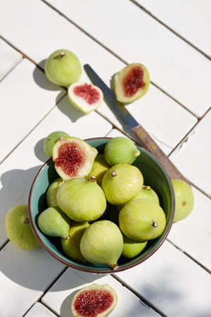 Fresh organic green figs bowl on a white wooden table in the garden outdoors, copy spaceの写真素材