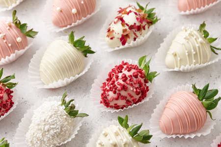 White and pink chocolate dipped strawberries on white tableの写真素材
