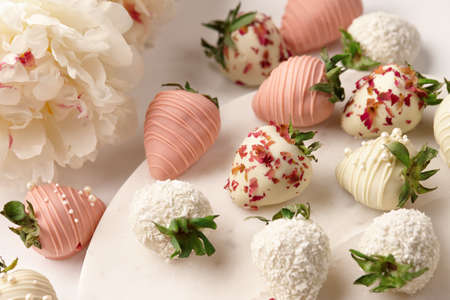 White and pink chocolate dipped strawberries on white tableの写真素材