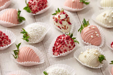 White and pink chocolate dipped strawberries on white tableの写真素材