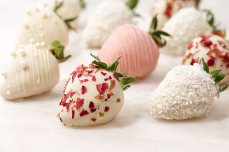 White and pink chocolate dipped strawberries on white tableの写真素材