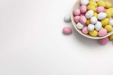 Egg shaped glazed chocolate candies for Easter holiday on white background, copy spaceの写真素材