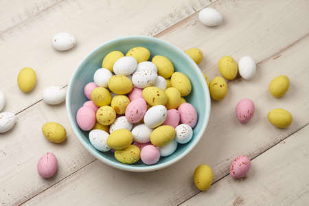 Egg shaped glazed chocolate candies for Easter holiday on white wooden planksの写真素材