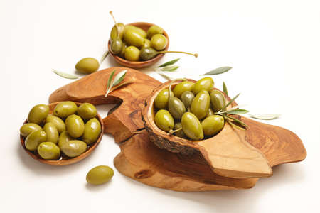 Green olives in wooden bowls on white background. Mediterranean cuisine.の写真素材