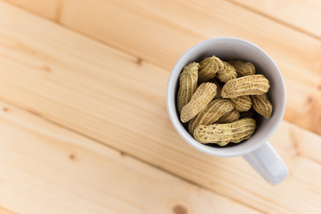 Peanut in Cup on wooden table の写真素材