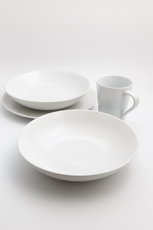 Clean empty ceramic plates and cups isolated on whiteの写真素材