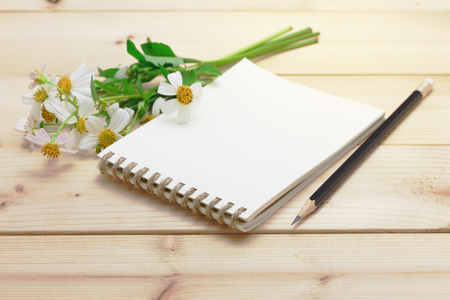 Notepad with pencil and grass flower on the wood backgroundの写真素材