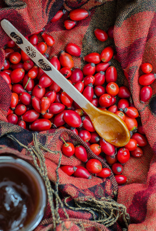 Rosehip berries and a wooden spoon with jam on fabric terracotta colorの写真素材