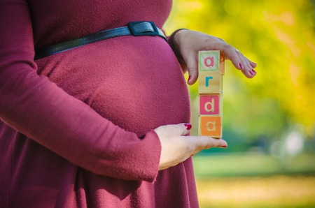 Close-up of letters on blocks and pregnant belly outdoor in the parkの写真素材