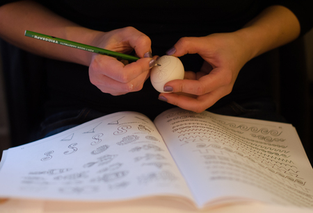 Easter eggs. Plain egg and pensil in hands drawing the patternの写真素材