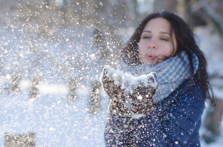 Portrait of pretty girl blowing the snowflakes from handsの写真素材