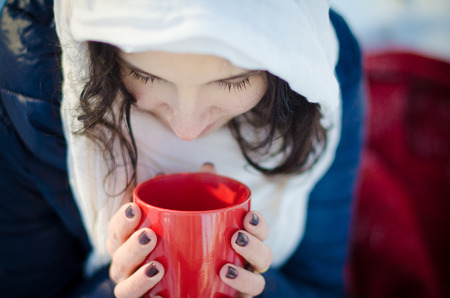 Close up of pretty girl who holding and looking down inside the red cupの写真素材
