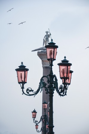 Street lamp and a monument against the white sky, Italyの写真素材