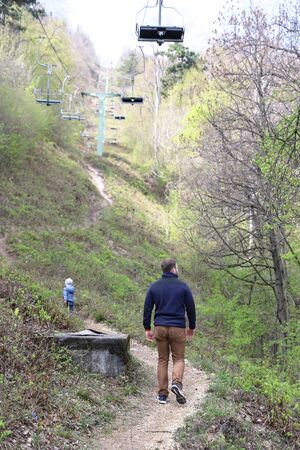 Family walk or hike on trail under chairlift in early spring, April on Buda hillsの写真素材