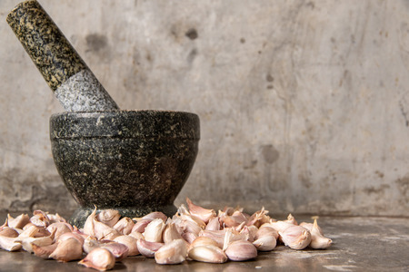 Garlic with stone mortar on top of cement table.の写真素材